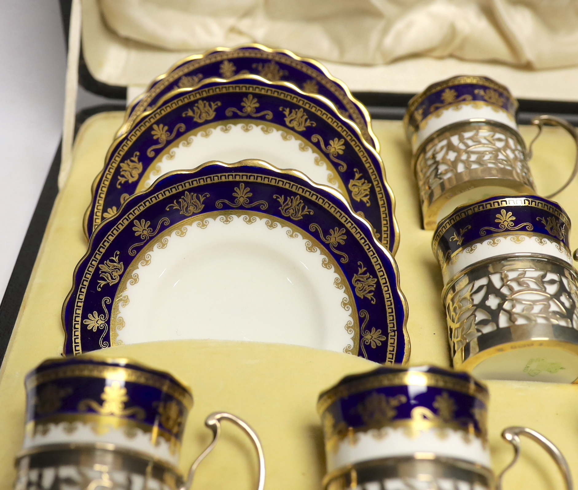 A cased George V set of six Aynsley coffee cans and saucers, the cans with pierced silver holders, C.S. Green & Co, Birmingham, 1924, can 57mm.